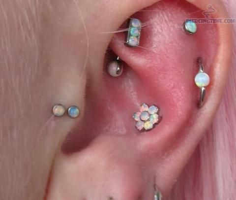 a person with pink hair has several piercings on their left side of the ear