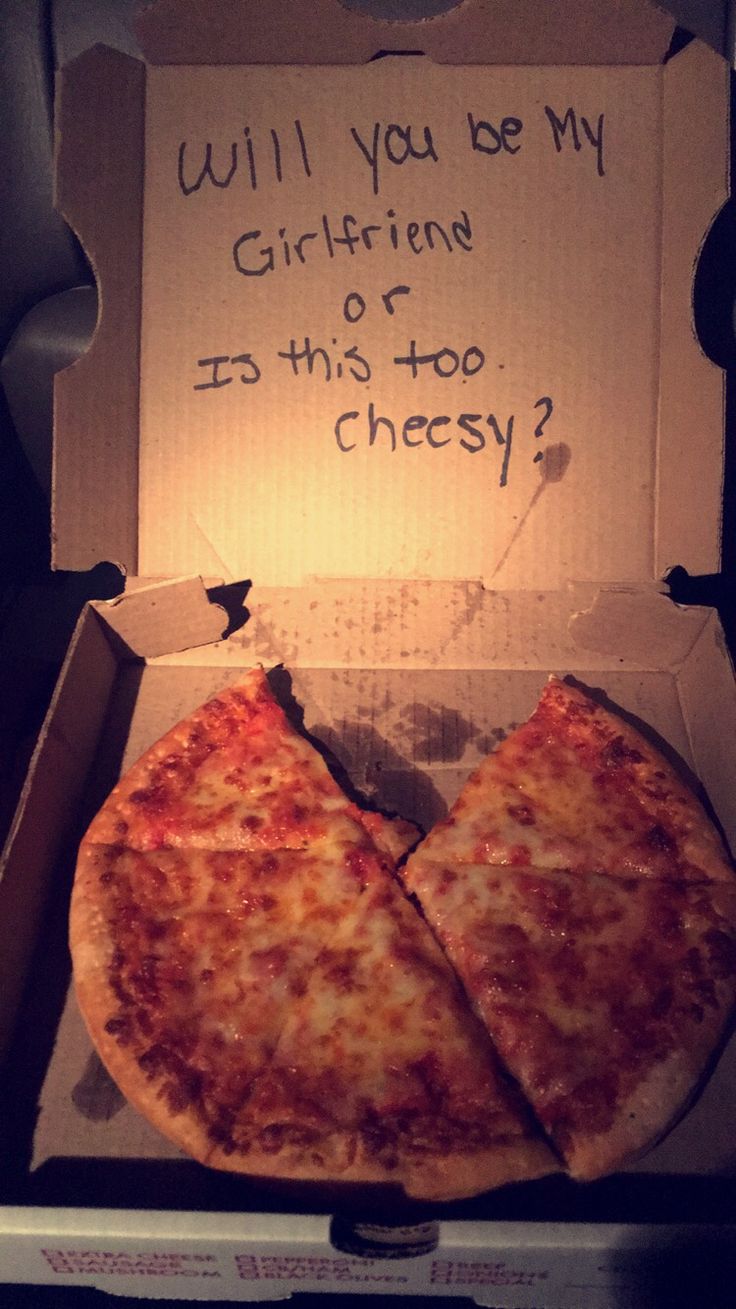 a box with two slices of pizza in it that says, will you be my girlfriend or is this too cheesy?