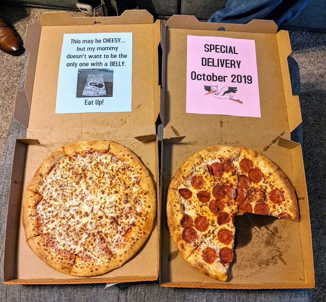 two pizzas are sitting in boxes on the floor with signs about their respective delivery