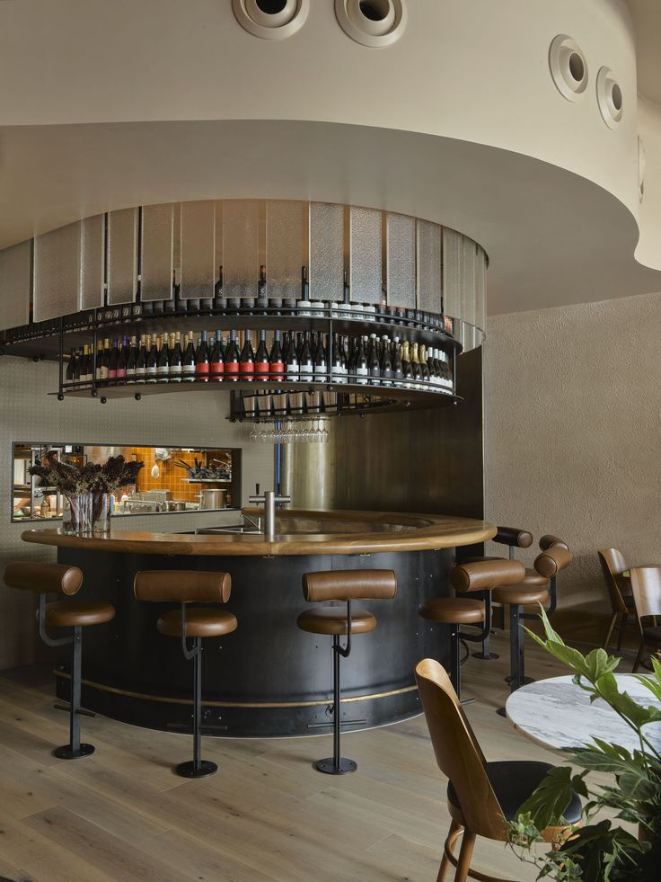 a bar with stools and bottles on the wall