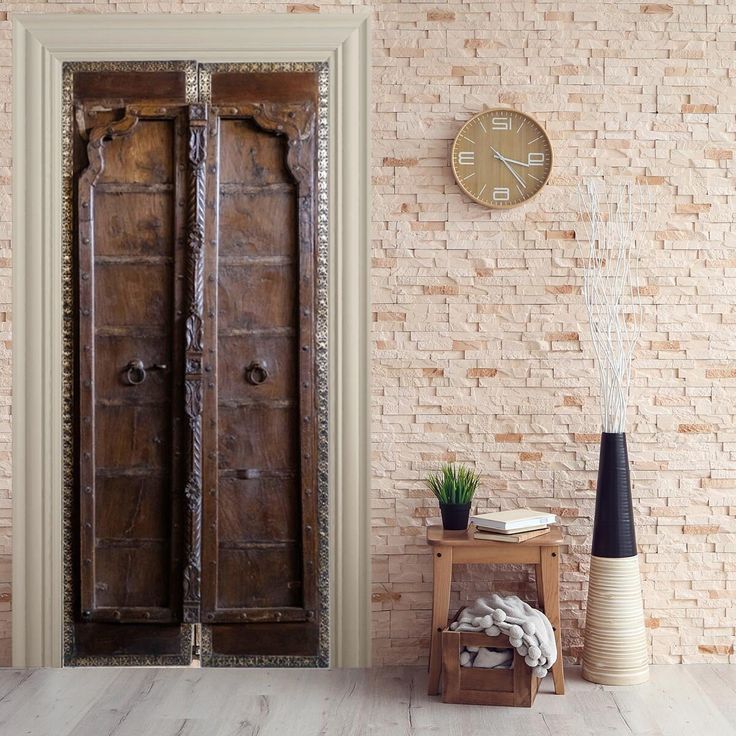 an old wooden door in a brick wall with a clock on the wall behind it