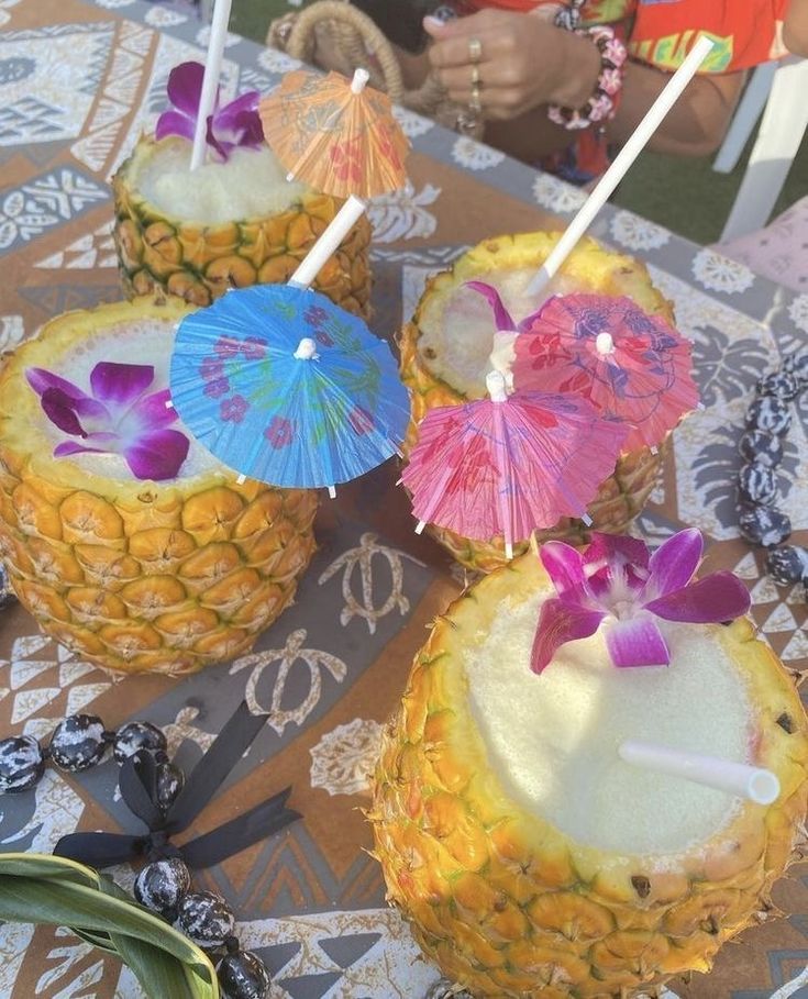 three pineapples with umbrellas sitting on top of a doily covered table