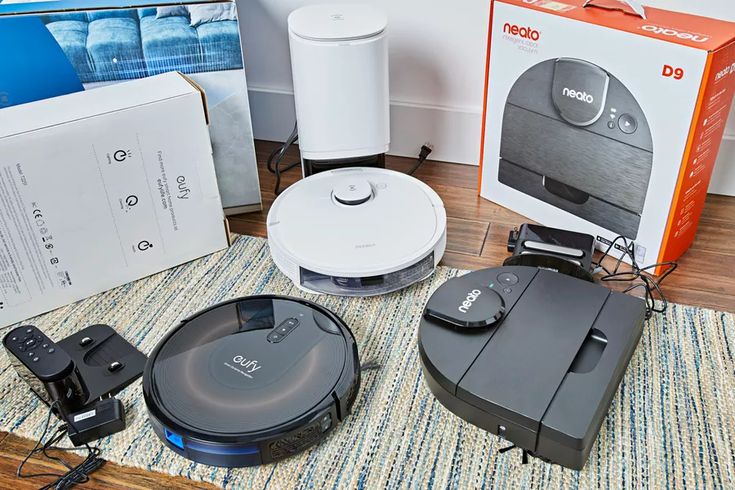 three different types of robotic vacuums sitting on the floor next to boxes and cords