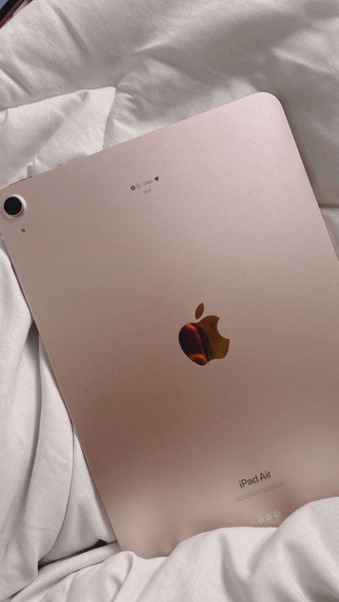 an apple ipad sitting on top of a white bed sheet with the cover pulled down