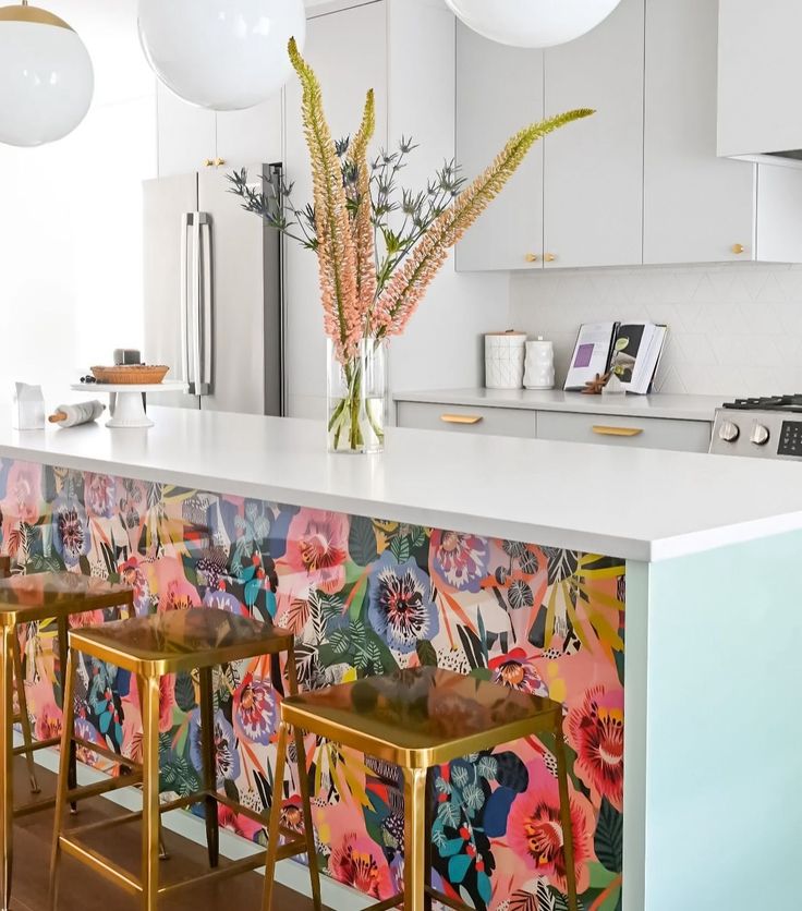 a kitchen with floral wallpaper and gold stools in front of an island counter