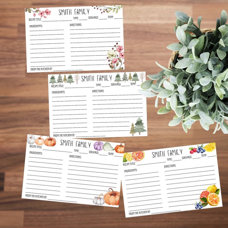 three place cards with flowers and leaves on them, sitting next to a potted plant