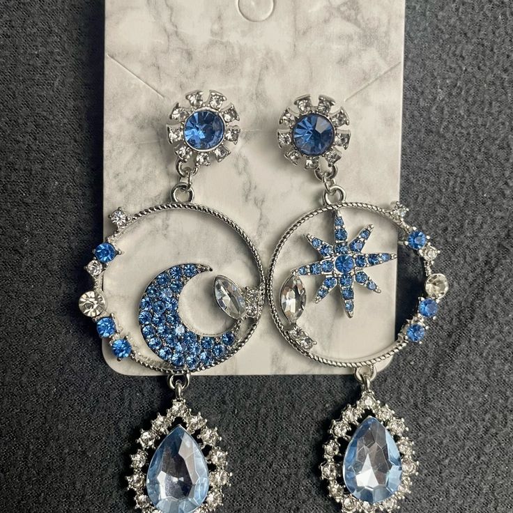 Gorgeous Blue Moon And Star Earrings, Dangle Earrings The Timeless Combination Of Blue And Silver In These Earrings Ensures They Can Complement A Wide Range Of Outfits. Whether You're Dressing Up For A Night Out Or Adding A Touch Of Elegance To Your Everyday Look, These Earrings Will Effortlessly Elevate Your Style. With These Earrings, You Can Add A Touch Of Celestial Elegance To Your Style And Stand Out From The Crowd. Blue Dangle Hoop Earrings, Blue Star-shaped Jewelry For Party, Blue Metal Dangle Hoop Earrings, Celestial Blue Pierced Earrings, Blue Celestial Pierced Earrings, Blue Celestial Round Earrings, Blue Metal Crystal Earrings, Blue Crystal Metal Earrings For Pierced Ears, Blue Metal Drop Clip-on Earrings