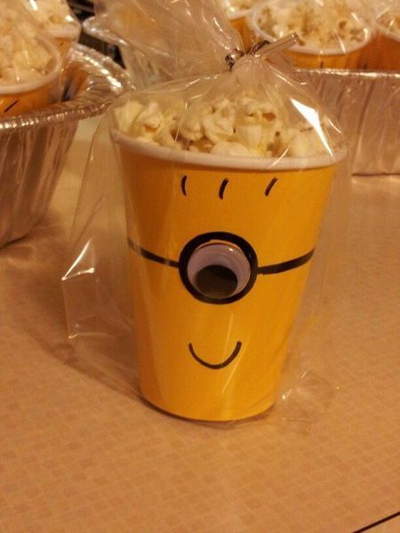 a yellow cup filled with popcorn sitting on top of a table next to tin foil