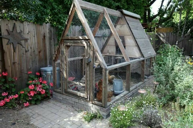 a chicken coop in the middle of a garden with flowers and plants around it,