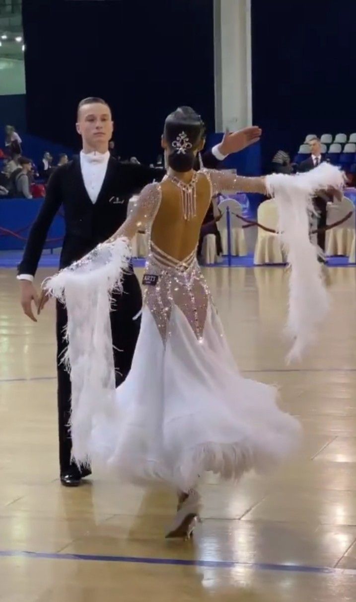 two people dressed in white and black dancing on a dance floor