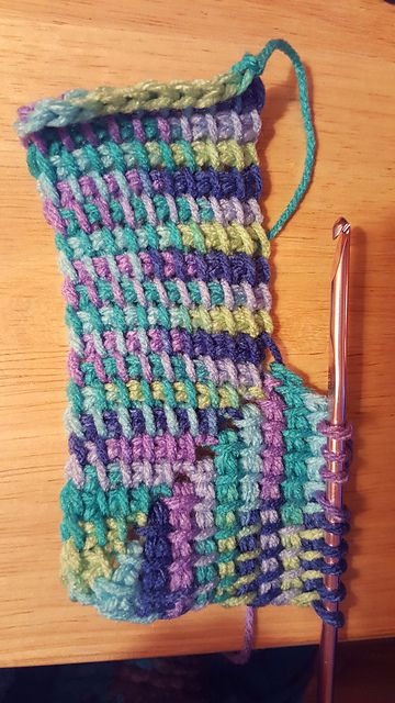 a close up of a crocheted object on a table with a knitting needle