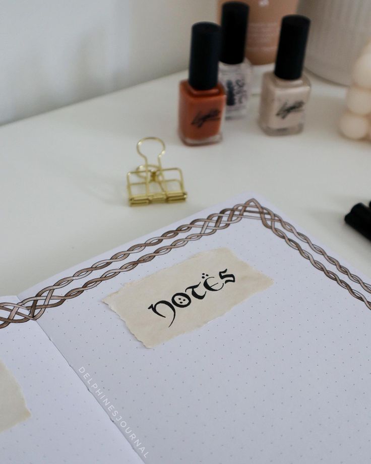 an open notebook sitting on top of a table next to nail polish and other items