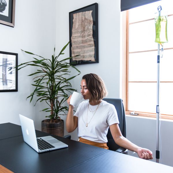 a woman sitting at a desk drinking coffee