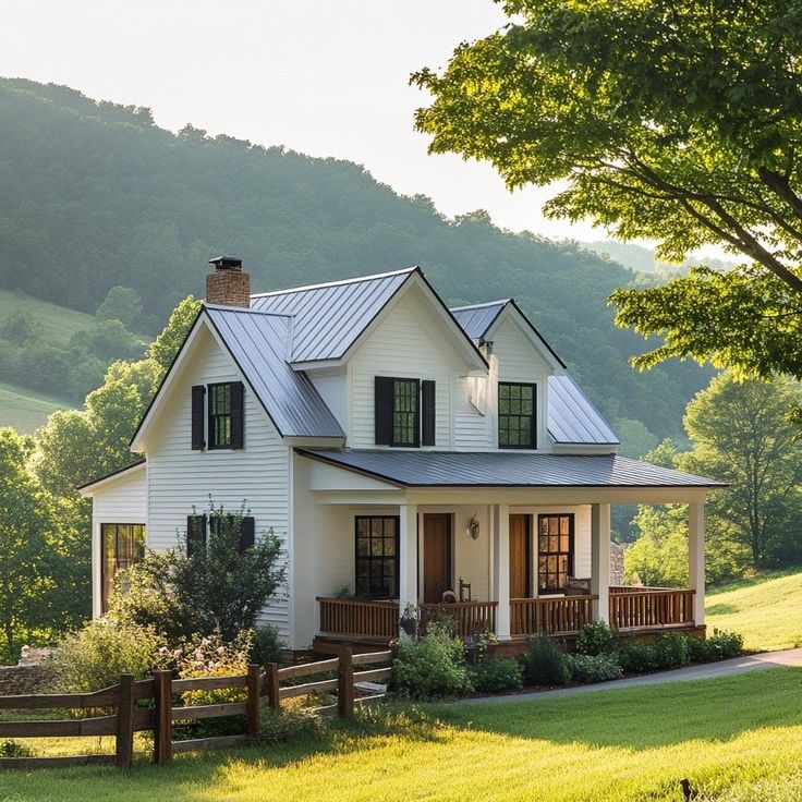 a white house with black shutters on the front and side windows, surrounded by lush green hills