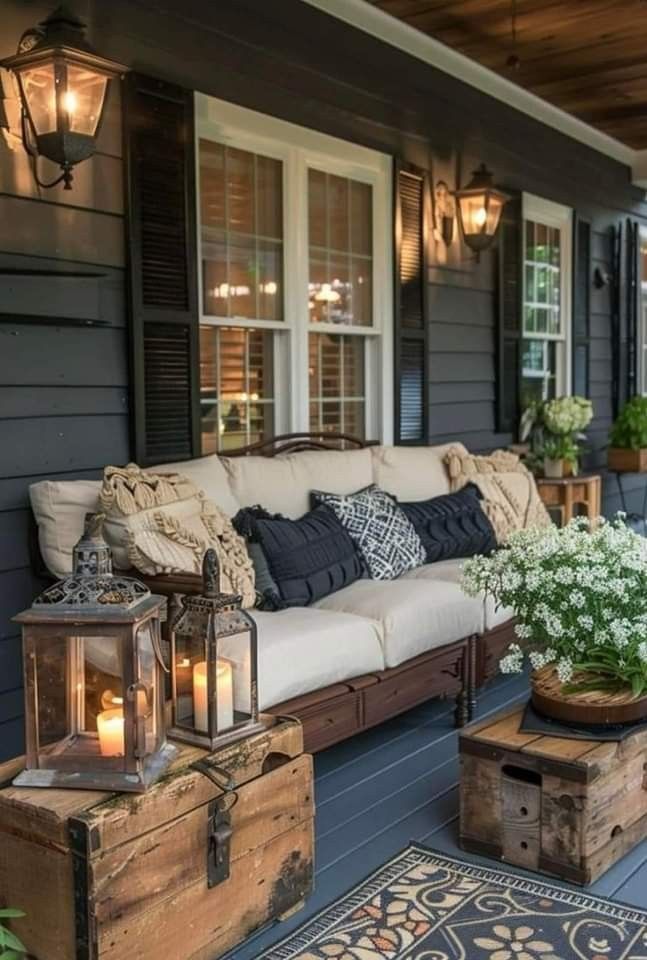 an outdoor living area with couches, tables and lanterns on the side of the house