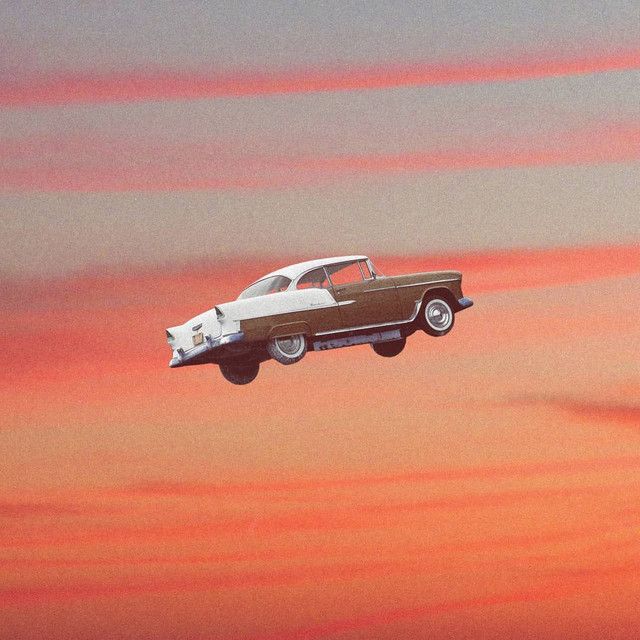 an old car flying through the sky with clouds in the background