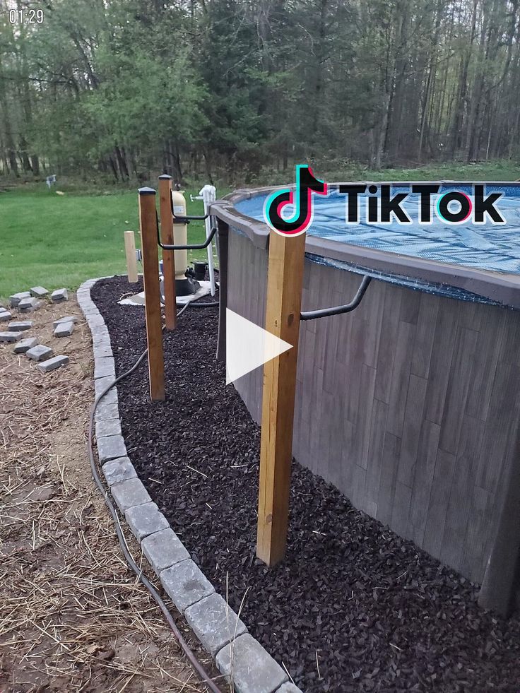 an above ground swimming pool surrounded by rocks and wood posts with the words tiktok on it