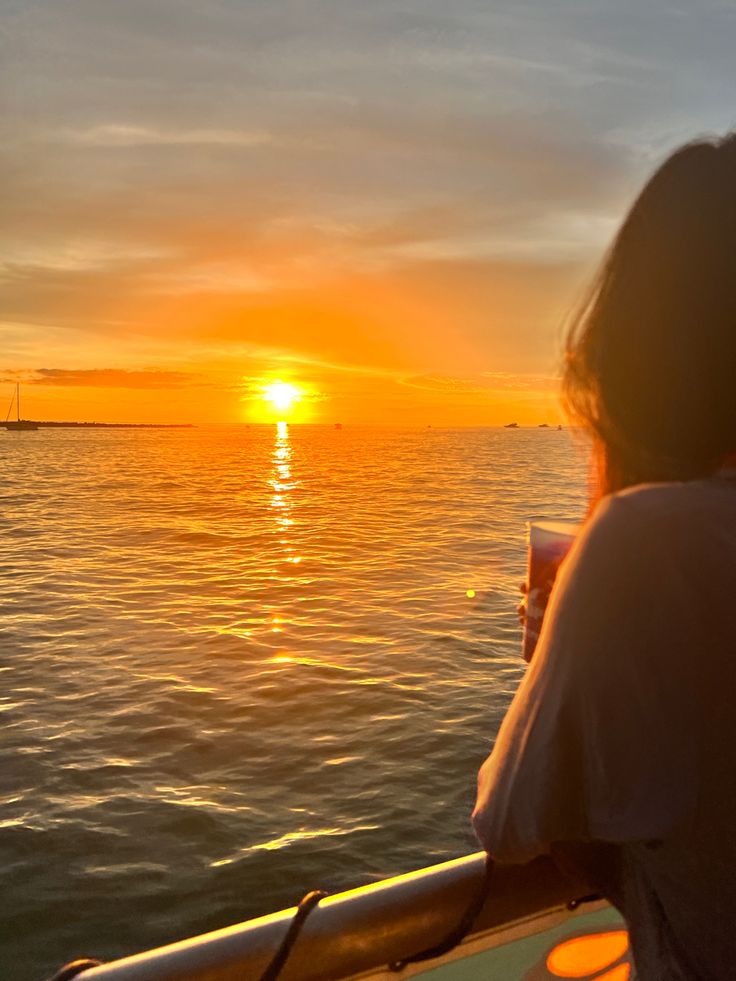 a person sitting on a boat watching the sun set