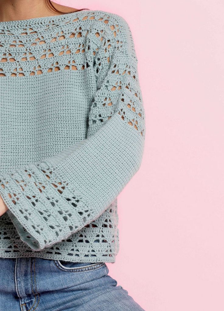 a woman wearing a blue sweater with crochet on the shoulders and arms crossed