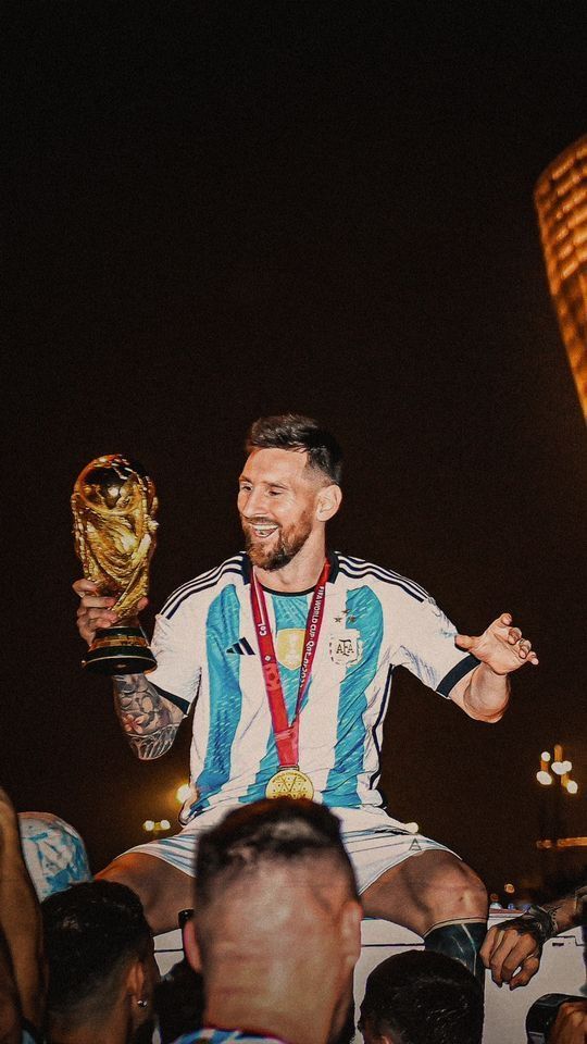 a man sitting on top of a bed holding a trophy