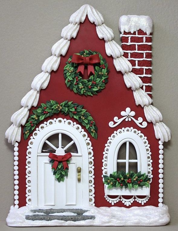 a red and white gingerbread house with wreaths on it