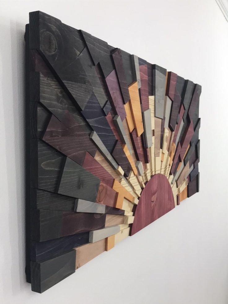 a wooden wall hanging on the side of a white wall with wood strips in it