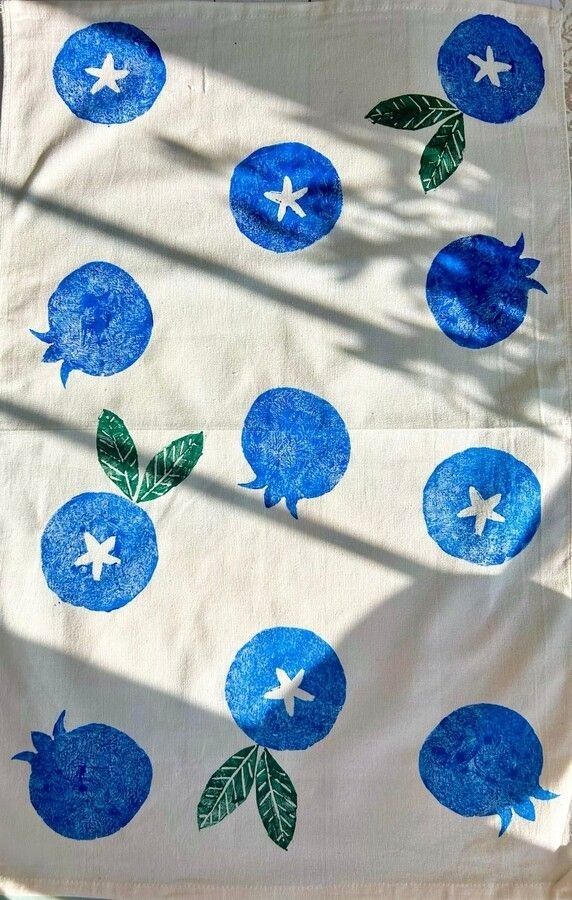 a blue and white table cloth with fruit on it's side, in the sunlight