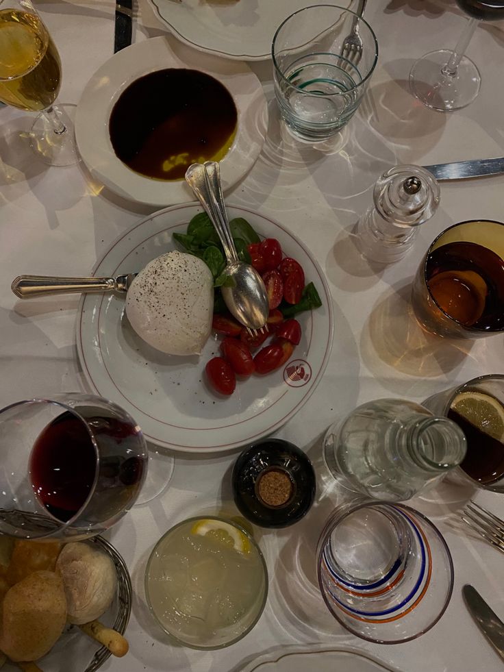 an assortment of food and wine on a table with glasses, spoons and utensils