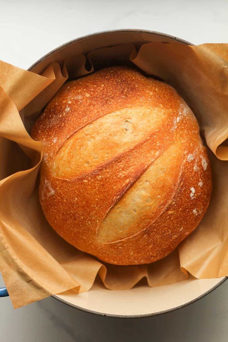 a round loaf of sourdough bread in a paper bag with text overlay