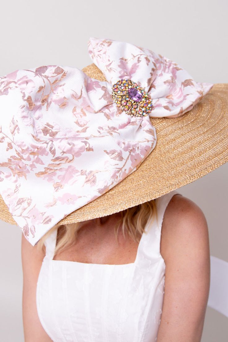 Step into the limelight with our breathtaking My Fair Lady Hat! This opulent piece, reminiscent of Audrey Hepburn's iconic elegance, is adorned with a dazzling brooch filled with shimmering jewels. Its gold hue and impressive 8" brim are sure to capture attention wherever you go. Adding to its allure is an oversized luxurious pink and gold bow, delicately gracing the brim and elevating your ensemble to new heights of sophistication. With an adjustable sweatband ensuring a secure and comfortable Luxury Gold Wide Brim Hat, Luxury Gold Hat For Kentucky Derby, Gold Curved Brim Hat For Kentucky Derby, Elegant Rhinestone Hat For Spring, Gold Evening Hat For Spring, Elegant Summer Hats With Rhinestones, Gold Hats With Curved Brim For Formal Occasions, Gold Curved Brim Hat For Formal Occasions, Elegant Wide Brim Hat With Rhinestones