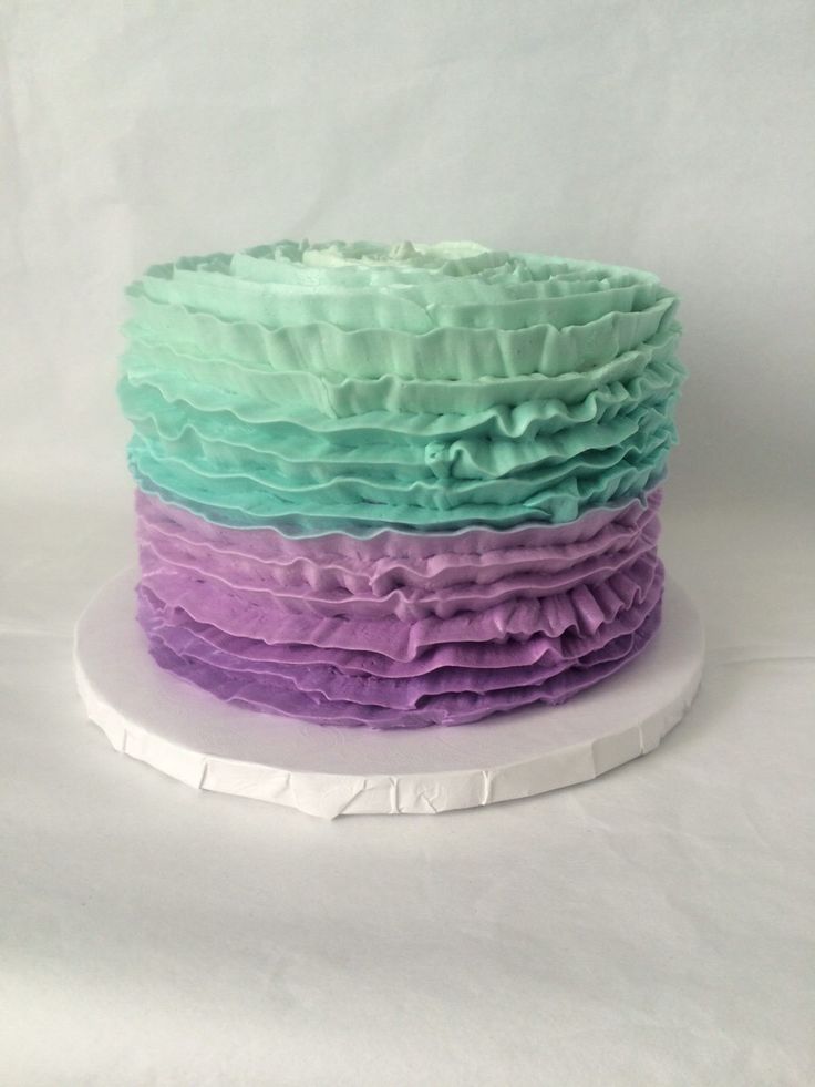 a multi colored cake with ruffles sitting on top of a white platter