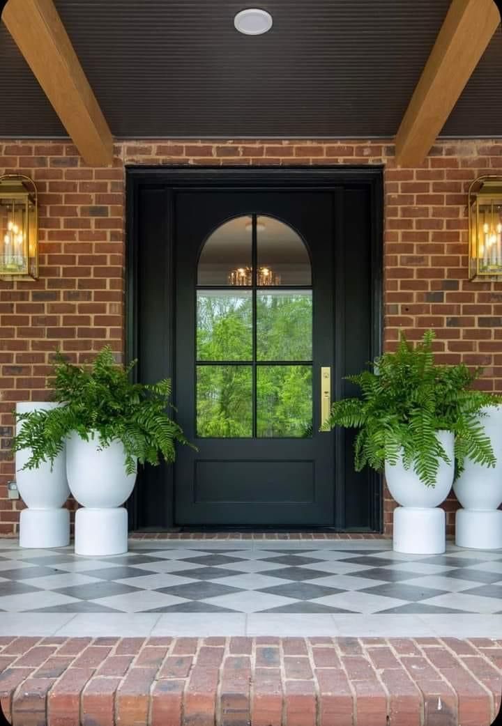 two large white planters sitting in front of a black door