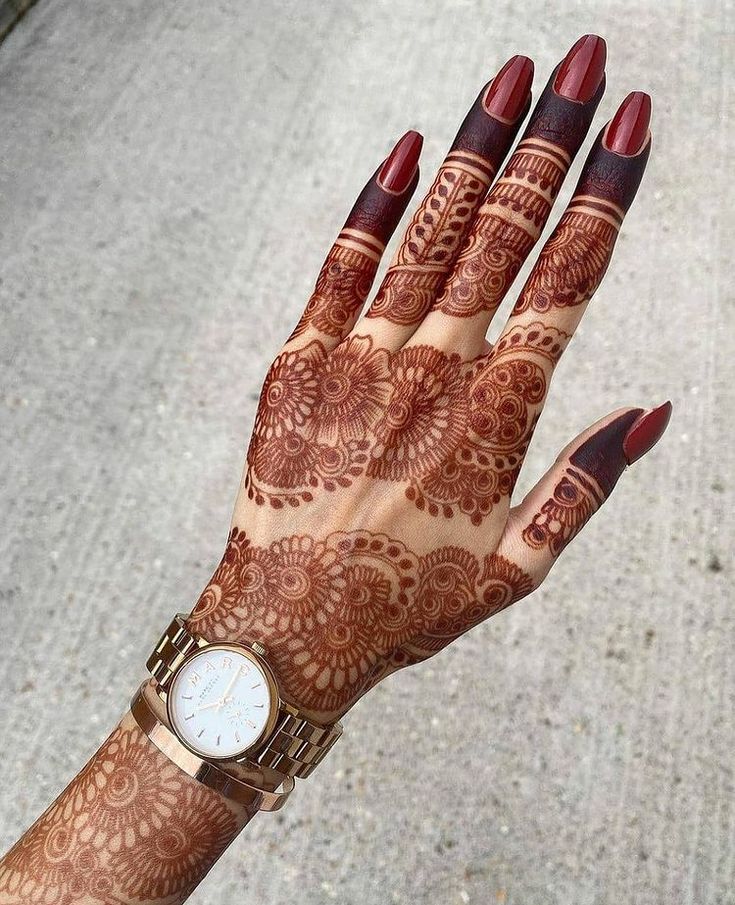 a woman's hand with henna tattoos on it and a watch around her wrist