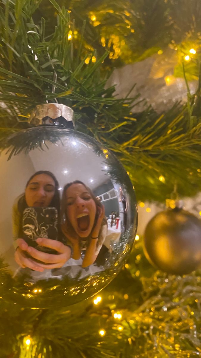 an ornament hanging from a christmas tree with two people in the middle and one person taking a selfie