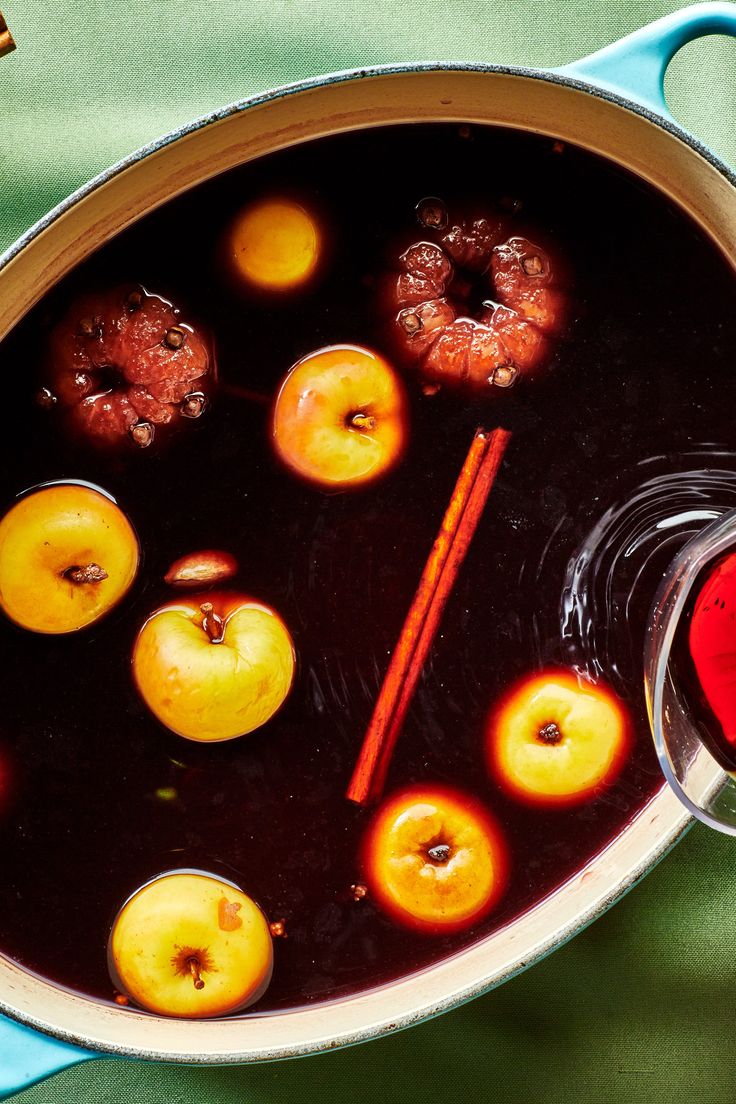 a pot filled with liquid sitting on top of a green table next to donuts