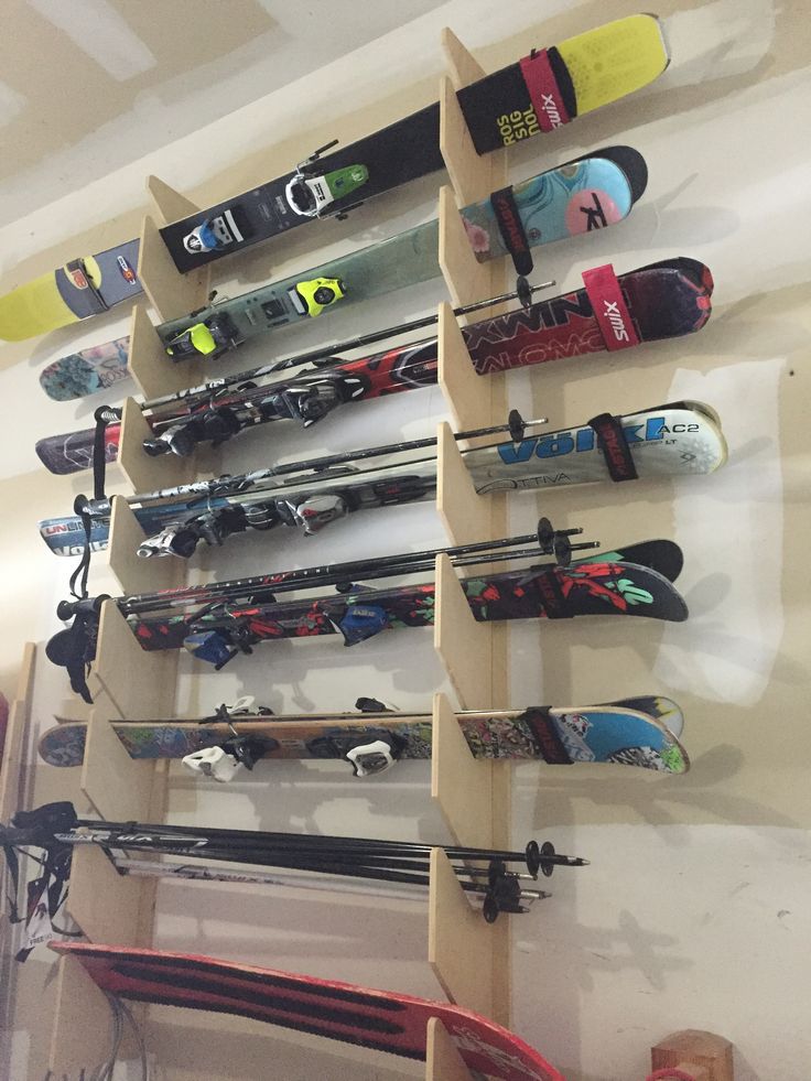 a rack with skis and snowboards mounted to the side of a wall in a room