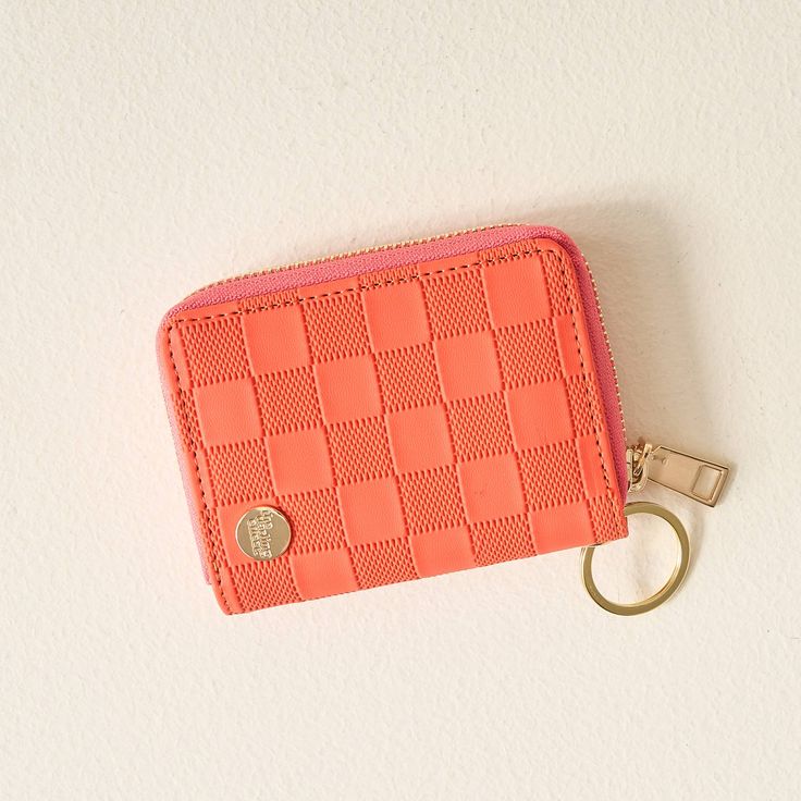 an orange purse with a gold keychain on it and a pink card holder