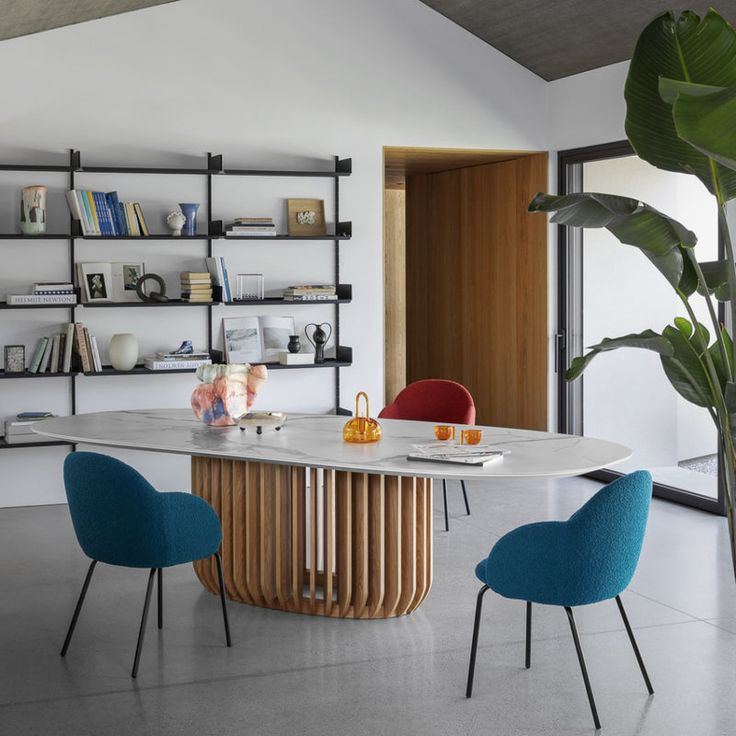 a dining room table with chairs around it and bookshelves on the wall behind it