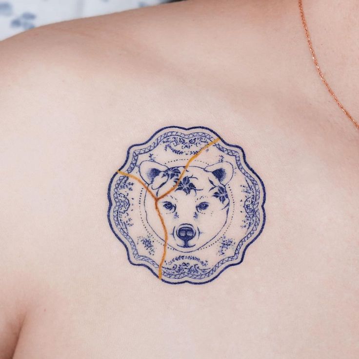 a close up of a person with a tattoo on their shoulder and chest, wearing a bear head