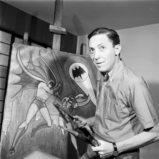 a man is holding a paintbrush in front of a batman painting