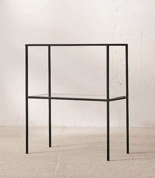 a glass shelf with black metal frame against a white wall