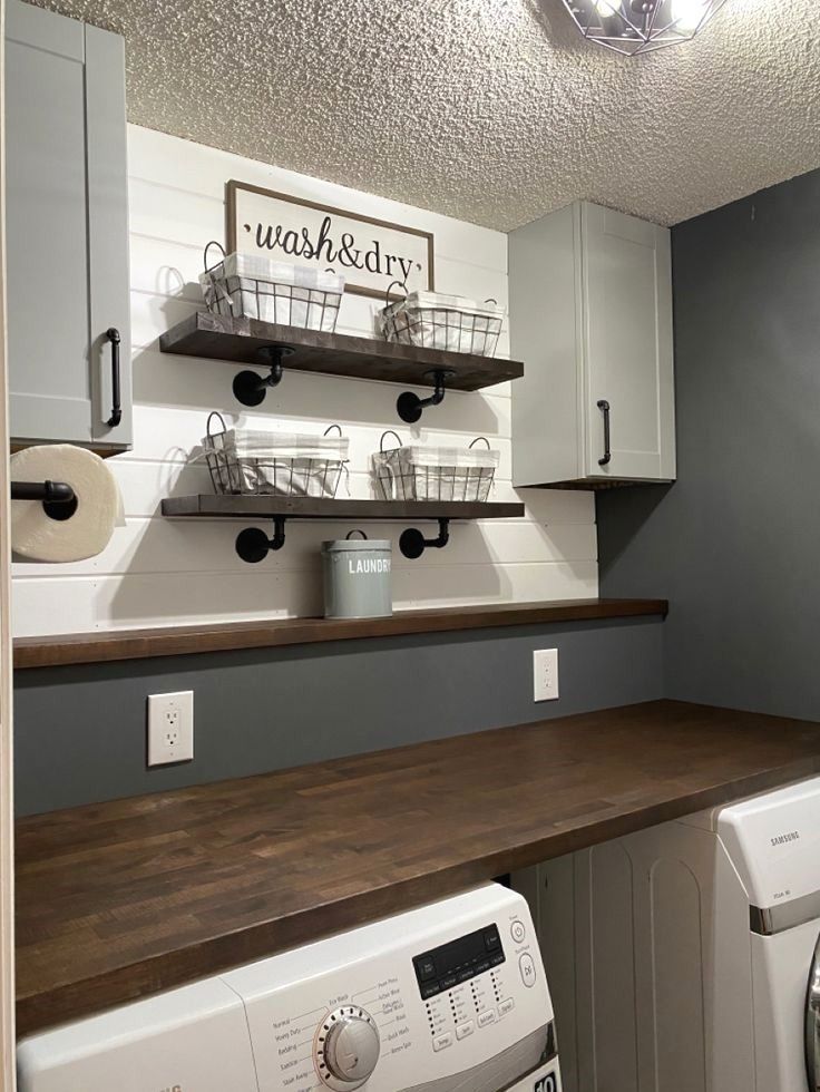 a washer and dryer sitting in a room next to a shelf with baskets on it