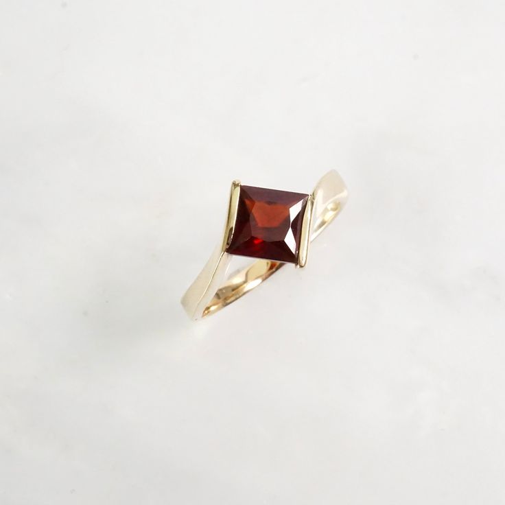 Love the way this princess cut Garnet is set in this ring! It's Gorgeous and unique.  A classic by-pass design with the sides of the gold becoming a part of the low profile design. Garnets are said to be the stone of love and friendship, and it's also January's birthstone.  (PLEASE NOTE: There's a tiny hole near one of the corners of the ring which cannot be fixed. Barely noticeable but the price has been adjusted) genuine Garnet Princess-Cut Garnet dark red color (Pyrope Garnet) measures 7 mm f Princess Cut Ring, Pyrope Garnet, Dark Red Color, Garnet Birthstone, Gold Diamond Band, Alternative Engagement Ring, Diamond Stacking Rings, Princess Cut Rings, Love And Friendship