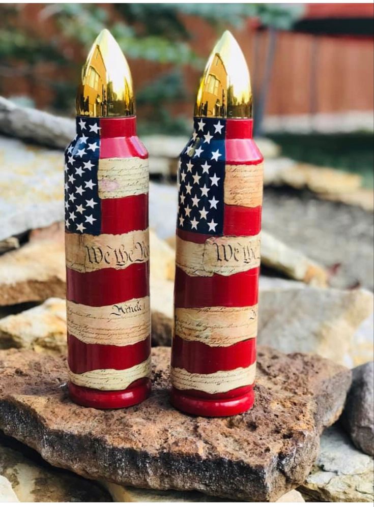 two red, white and blue firecrackers sitting on top of a rock