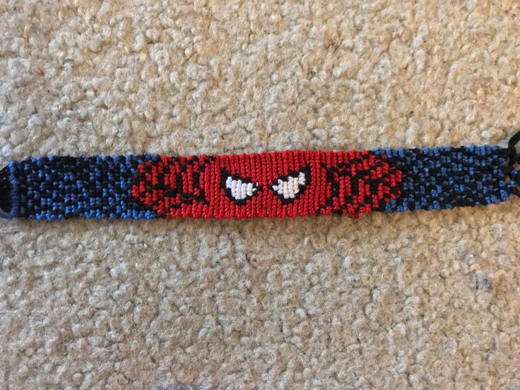 a red and blue beaded wristband with black metal clasps on carpeted area