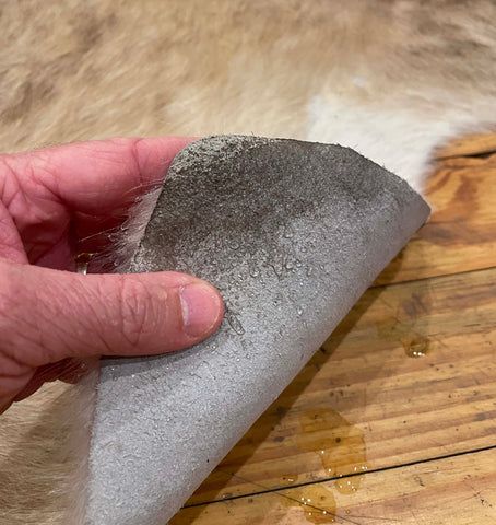 a hand is touching the tip of a piece of fabric on a wooden table top