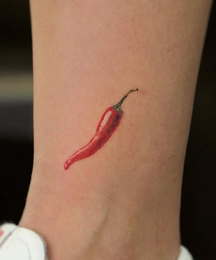 a small red chili pepper tattoo on the right side of the ankle, it's tiny