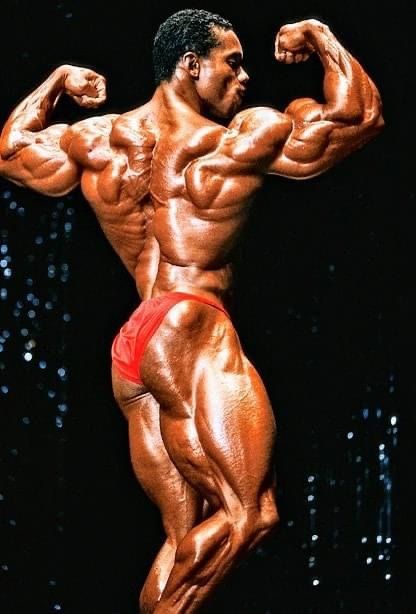 a bodybuilding man posing for the camera with his arms and legs spread out,