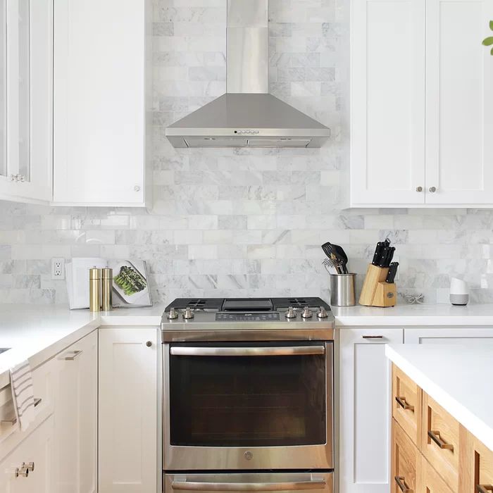 a stove top oven sitting inside of a kitchen next to white cupboards and drawers