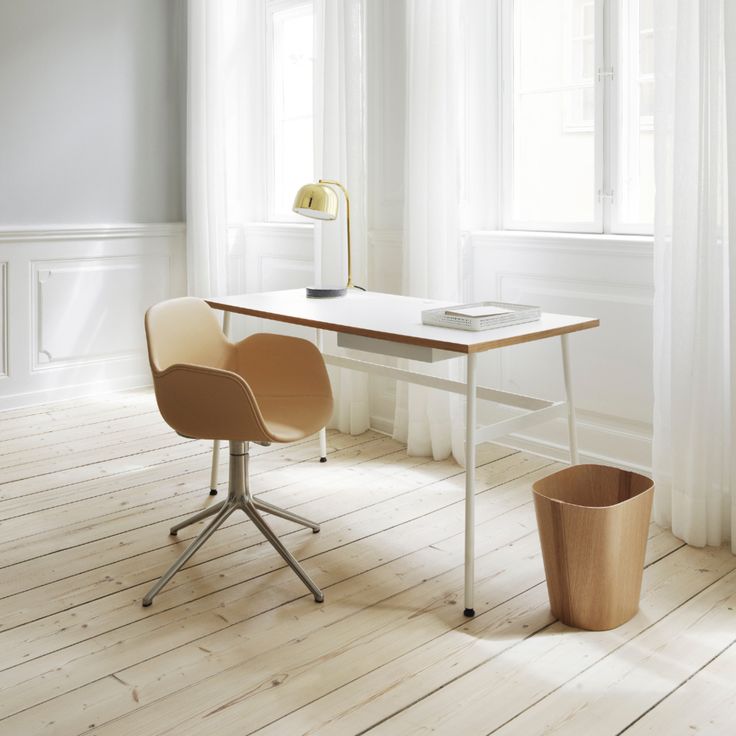 an empty room with a desk and chair next to a potted plant on the floor